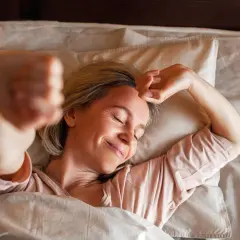 Finalmente dormo serena, come ho sconfitto l'insonnia. Una donna sorride nel letto, rilassata sotto le coperte.