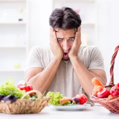 Uomo con espressione terrorizzata davanti a verdure fresche, simbolo di neofobia alimentare adulti.