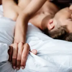 Coppia in intimità, un momento di passione e masturbazione di coppia tra lenzuola bianche.