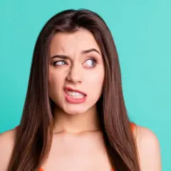Donna con espressione tesa, labbra serrate e sguardo di lato. Un'immagine che ricorda che si può guarire dai tic nervosi.
