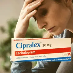 Donna con mal di testa tiene in mano una scatola di Cipralex, farmaco che serve per trattare depressione e ansia.