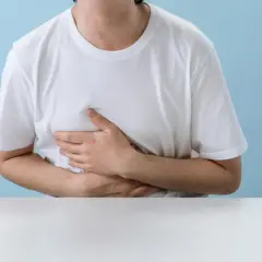 Persona con le mani sull'addome, che esprime disagio. Potrebbe soffrire di diarrea da stress.