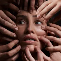 Volto di donna circondato da mani che la stringono, espressione di disagio, forse un simbolo del disturbo schizoide di personalità.