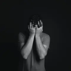 Uomo con le mani sul viso, in un momento di profonda tristezza. Finalmente sono guarito dalla disfunzione erettile.