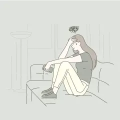 Ragazza seduta sul divano con la mano sulla fronte, pensieri confusi sopra la testa. Non voglio andare dallo psichiatra.