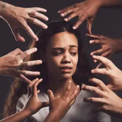 Una donna spaventata circondata da mani che simboleggiano manie di persecuzione.
