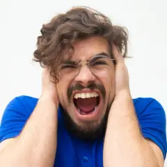 Uomo con mani sulle orecchie, urla disperato. Potrebbe essere un momento di attacchi di panico cosa fare per trovare sollievo.