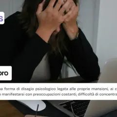 Donna con le mani tra i capelli davanti a un laptop, simbolo di ansia da lavoro.