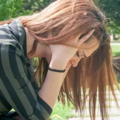 Ragazza con capelli rossi, mani tra i capelli, in cerca di tricotillomania rimedi naturali.