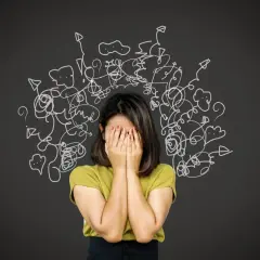 Donna con le mani sul viso, circondata da disegni caotici. Un'immagine che evoca la difficoltà nel come trattare un paranoico, con pensieri confusi e ansia.