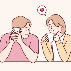 Coppia che sorseggia bevande calde, con un cuore che fluttua sopra di loro. Sembra che stiano iniziando a idealizzare una persona.
