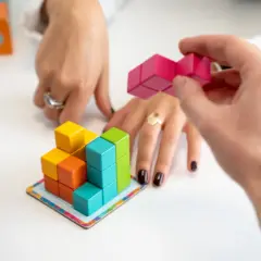 Mani che assemblano blocchi colorati, un gioco che stimola l'alto potenziale cognitivo.