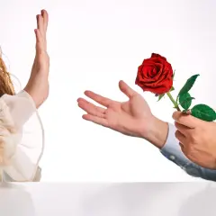 Una mano respinge una rosa rossa offerta da un uomo. Un'immagine che evoca il tema di come superare un rifiuto in amore.