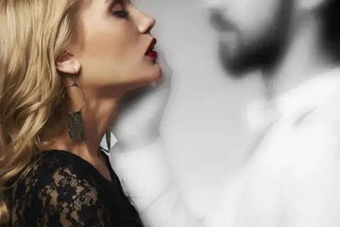 Donna bionda con labbra rosse e orecchino, accanto a una figura maschile sfocata. Un'immagine che evoca il tema di come comportarsi con chi fa ghosting.