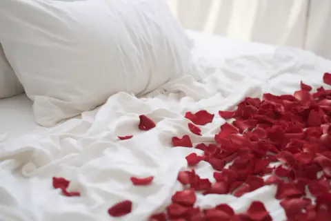 Letti bianchi con petali di rosa rossi sparsi, un invito a un momento di passione, perché dopo il ciclo si ha più voglia.