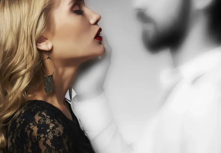 Donna bionda con labbra rosse e orecchino, accanto a una figura maschile sfocata. Un'immagine che evoca il tema di come comportarsi con chi fa ghosting.