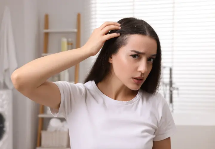 Donna preoccupata si tocca la testa, avvertendo un formicolio che potrebbe essere legato all'ansia.