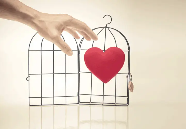 Mano che apre una gabbia con un cuore rosso dentro. Abbiamo fatto l'amore e non si fa sentire, il mio cuore è libero ma solo.