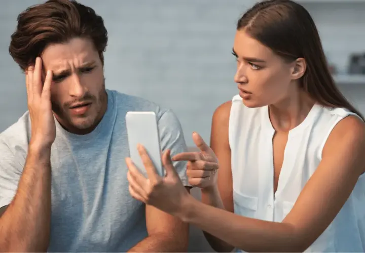 Coppia sconvolta guarda il telefono, affrontando il difficile percorso su come superare un tradimento.