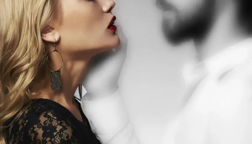 Donna bionda con labbra rosse e orecchino, accanto a una figura maschile sfocata. Un'immagine che evoca il tema di come comportarsi con chi fa ghosting.