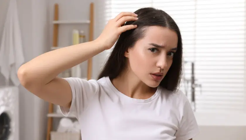 Donna preoccupata si tocca la testa, avvertendo un formicolio che potrebbe essere legato all'ansia.