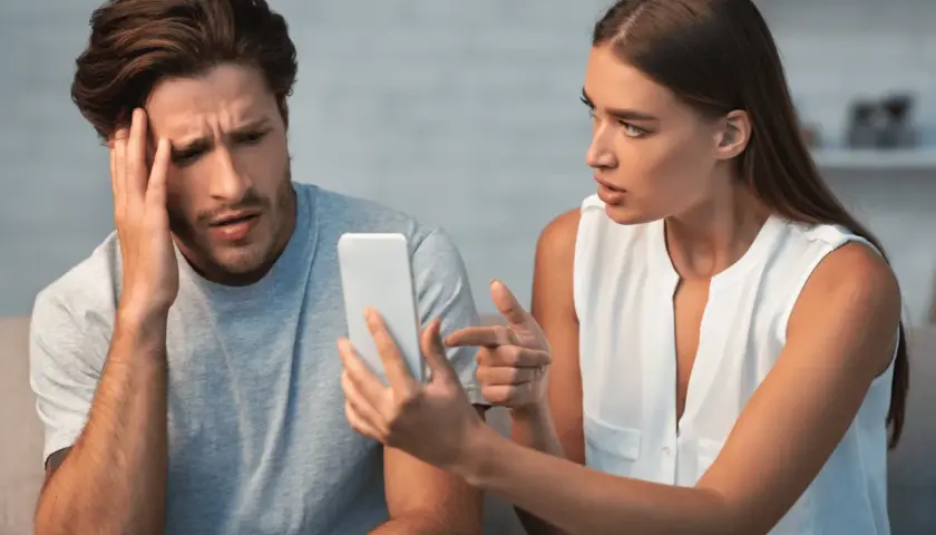 Coppia sconvolta guarda il telefono, affrontando il difficile percorso su come superare un tradimento.
