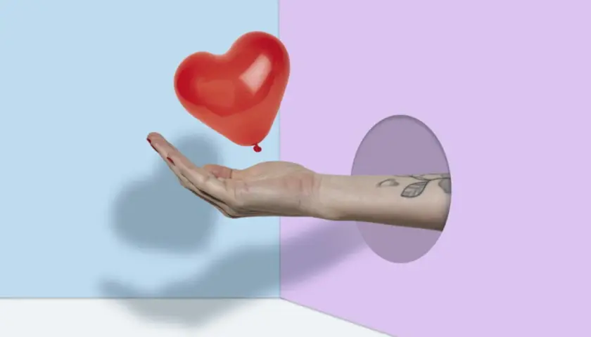 Mano che offre un palloncino a forma di cuore rosso, simbolo di frasi sull'amore puro.