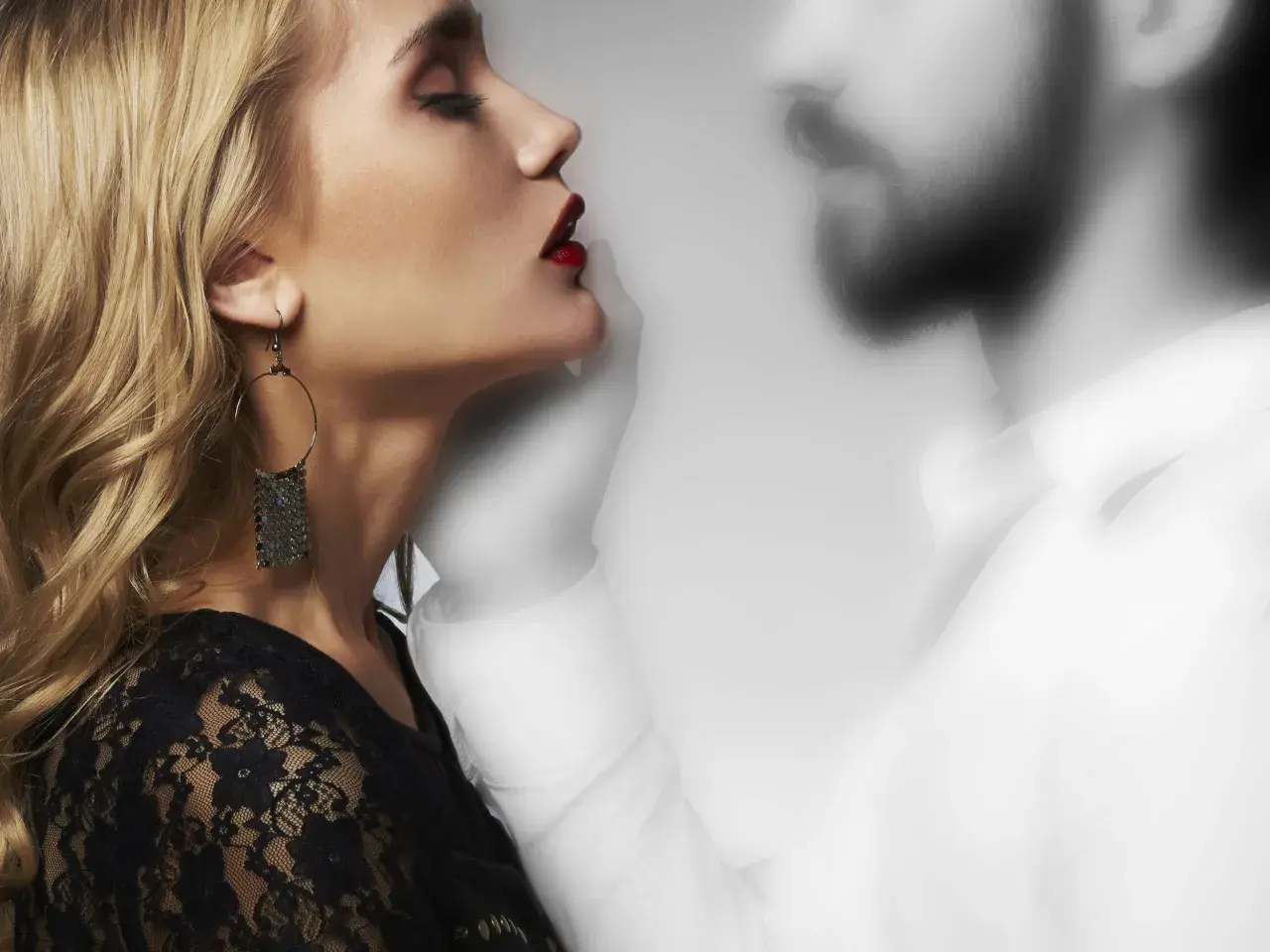 Donna bionda con labbra rosse e orecchino, accanto a una figura maschile sfocata. Un'immagine che evoca il tema di come comportarsi con chi fa ghosting.