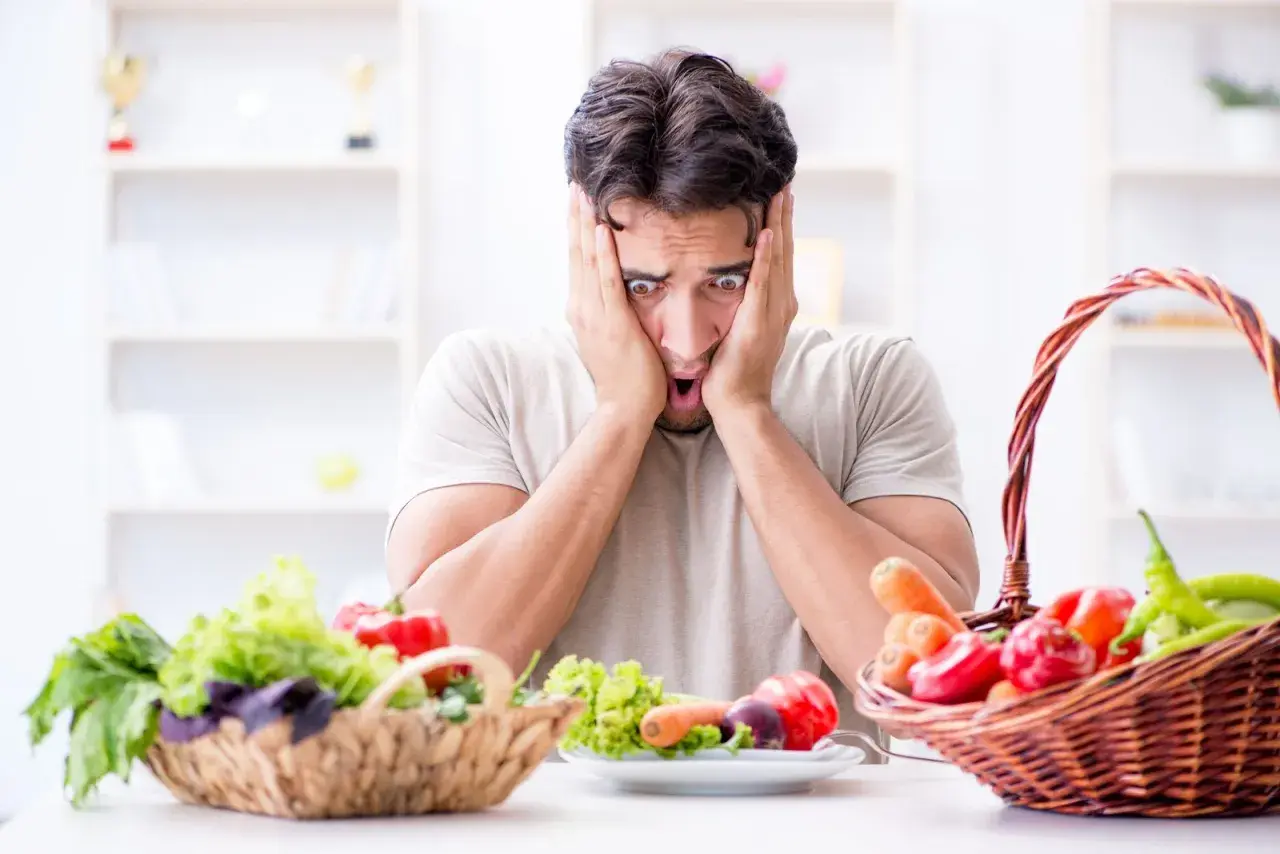 Uomo con espressione terrorizzata davanti a verdure fresche, simbolo di neofobia alimentare adulti.