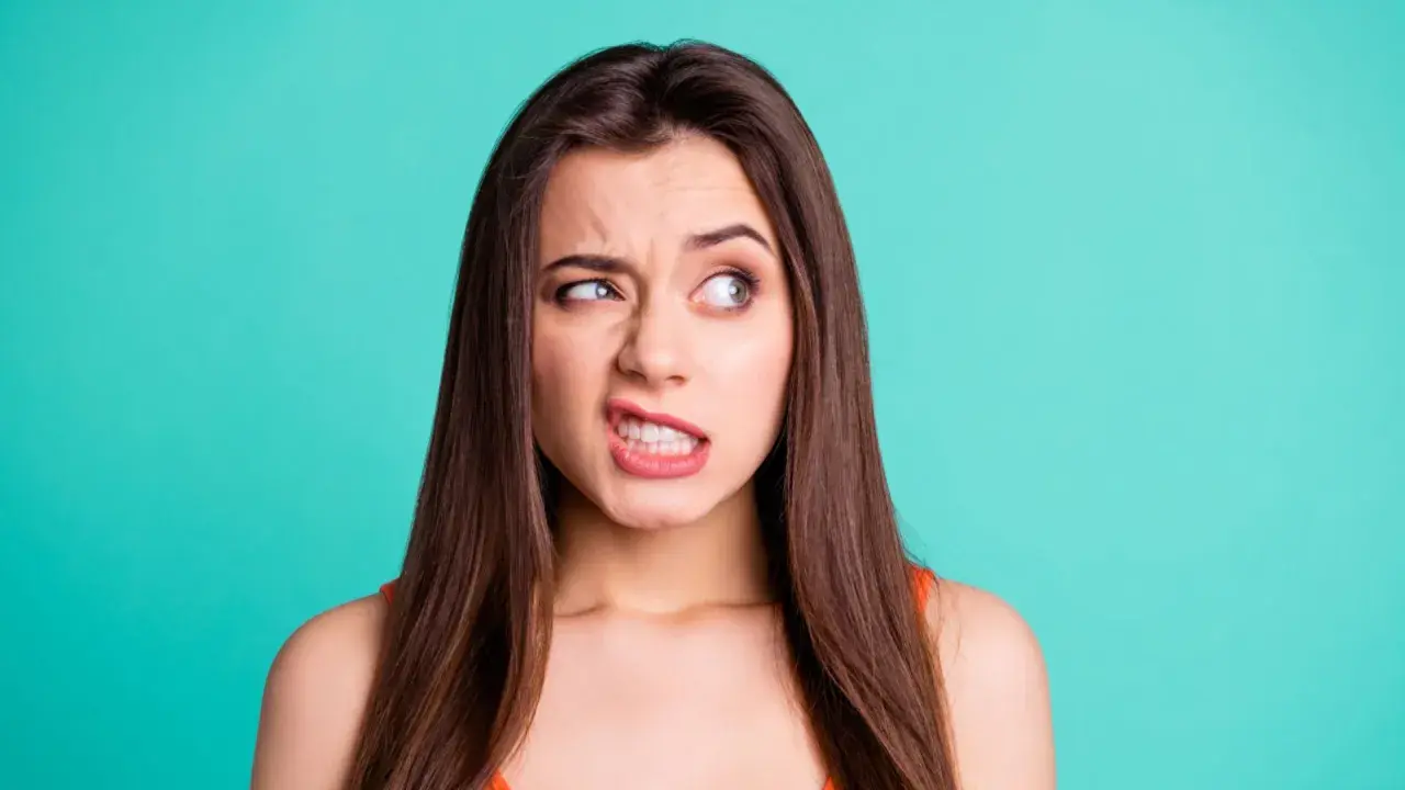 Donna con espressione tesa, labbra serrate e sguardo di lato. Un'immagine che ricorda che si può guarire dai tic nervosi.