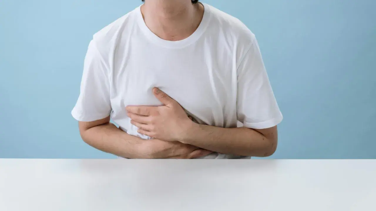 Persona con le mani sull'addome, che esprime disagio. Potrebbe soffrire di diarrea da stress.