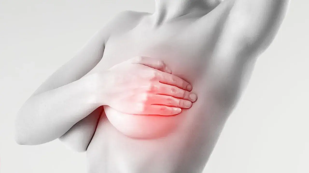 Mano che copre il seno con un'area rossa che indica bruciore e ansia.