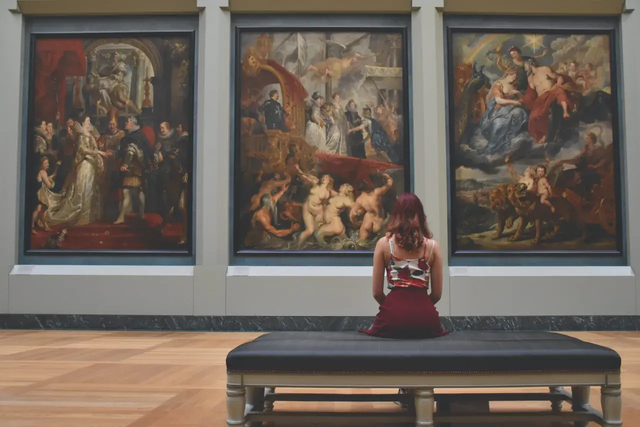 Una donna ammira tre grandi dipinti in un museo, forse provando la sindrome di Stendhal cos'è.