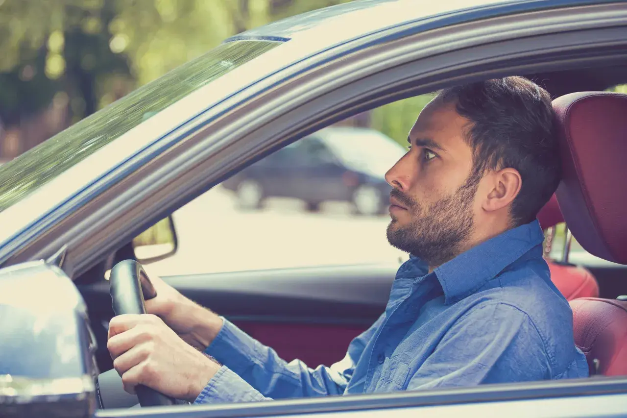 Uomo con espressione tesa al volante, forse a causa della paura di guidare.