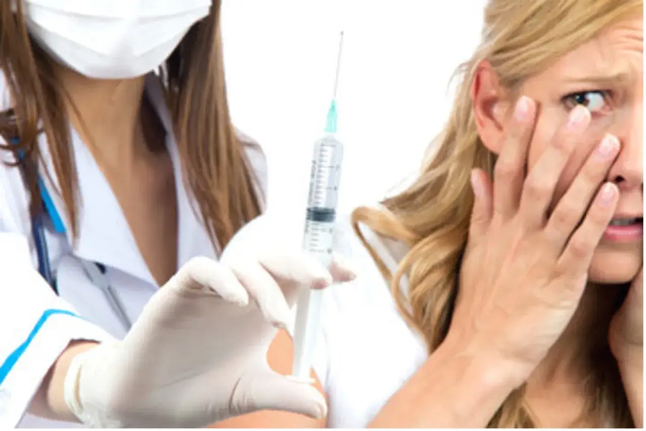 Una donna con espressione di paura degli aghi, copre il viso mentre un'infermiera con guanti bianchi tiene una siringa.