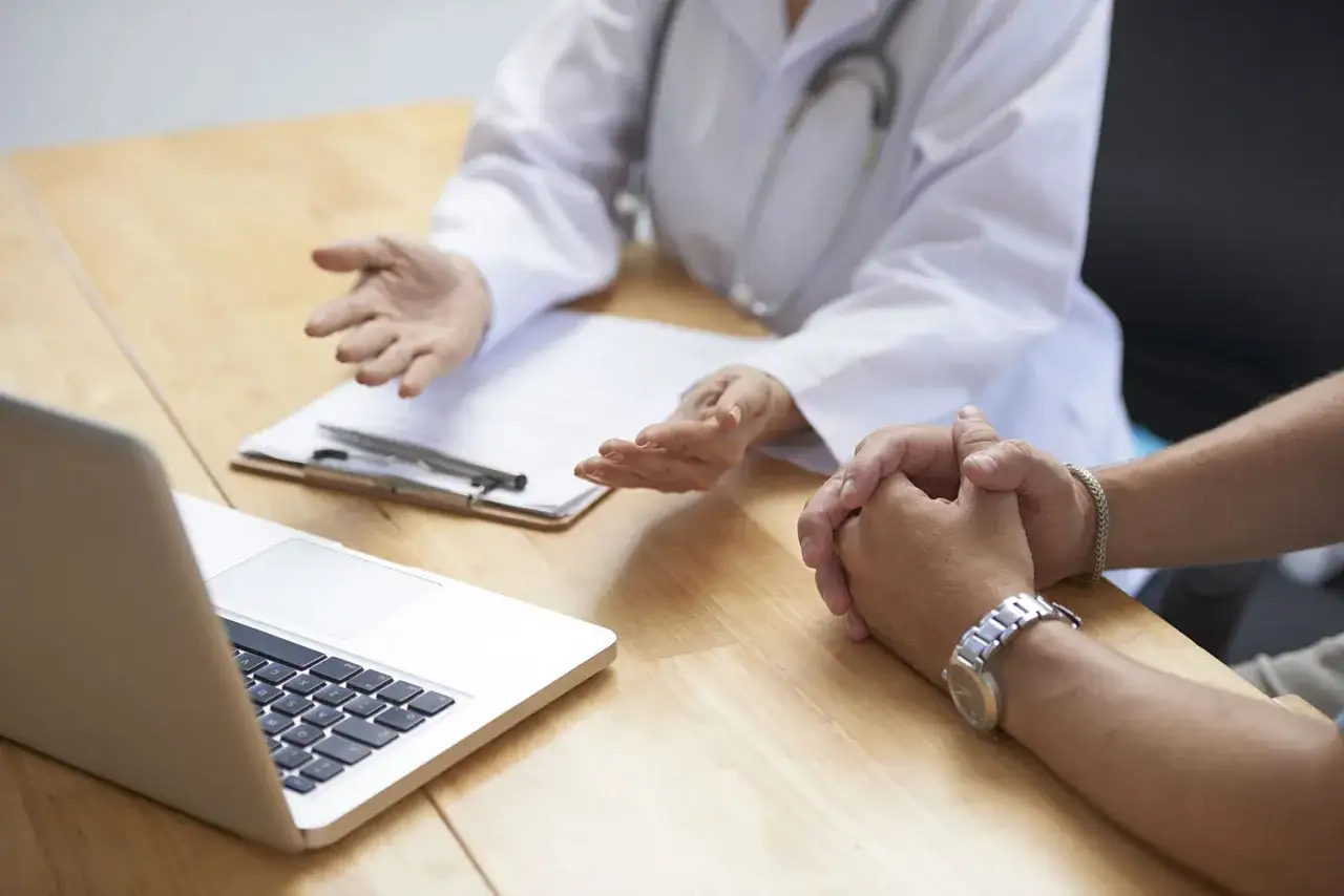 Medico con camice bianco e stetoscopio parla con paziente, discutendo opzioni terapeutiche. Il neurologo può prescrivere psicofarmaci.