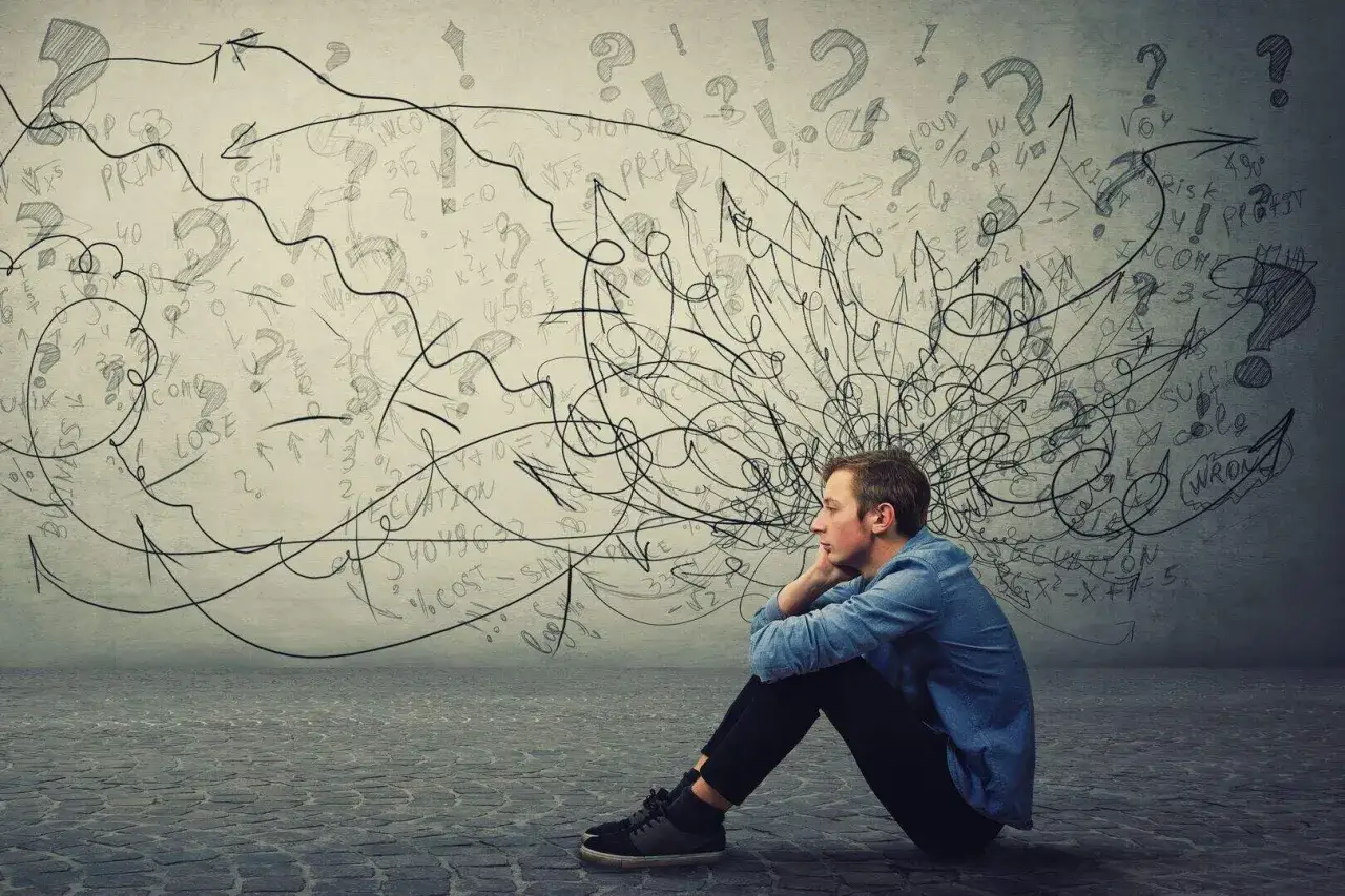 Ragazzo pensieroso seduto a terra, con la testa piena di grovigli di pensieri, formule matematiche e punti interrogativi. Forse è per questo che ho pensieri omicidi.