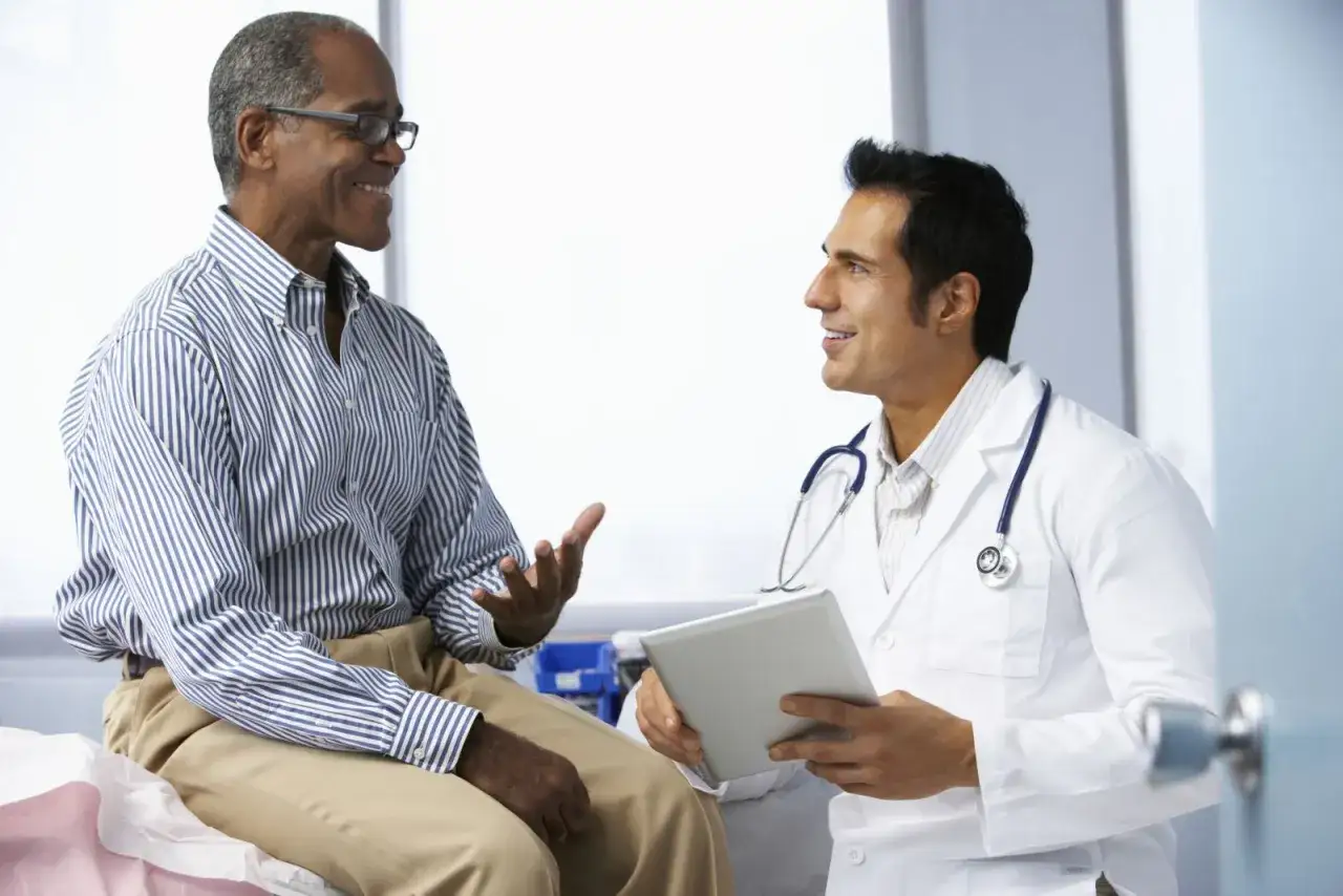 Un uomo sorride al suo medico, felice di aver trovato una soluzione: sono guarito dalla disfunzione erettile.