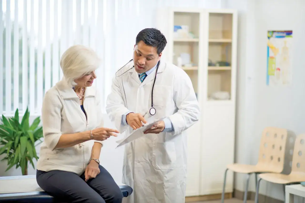 Medico e paziente discutono di diagnosi differenziale significato. La paziente indica un documento mentre il medico ascolta attentamente.