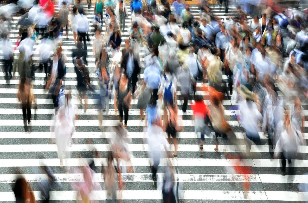 Un fiume di persone attraversa la strada, un vortice indistinto che evoca la paura di stare in mezzo alla gente.