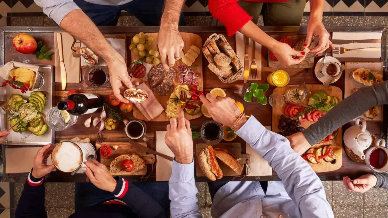 Un gruppo di adulti condivide un abbondante brunch, affrontando la neofobia alimentare con piatti vari e invitanti.